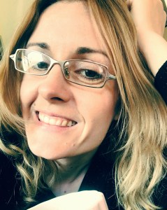 A smiling blond woman with glasses